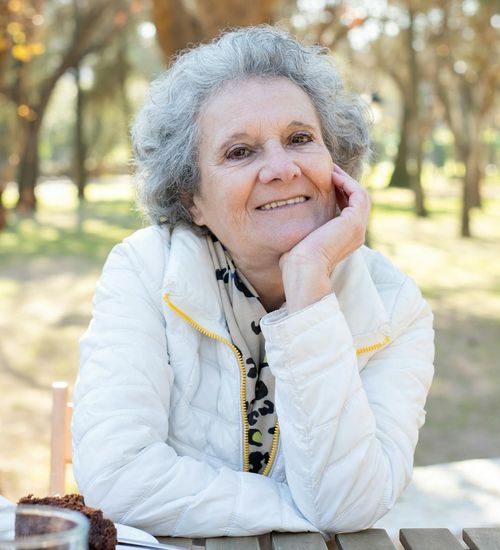 A person sitting peacefully outdoors, embodying a sense of well-being.